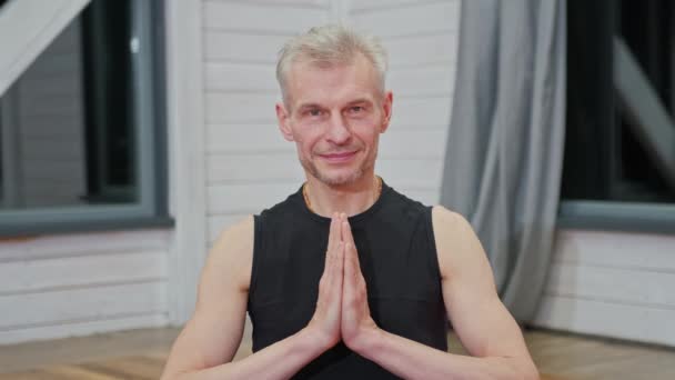 Retrato del hombre guapo en namaste posando cogido de la mano mientras disfruta de la meditación espiritual en el apartamento — Vídeos de Stock