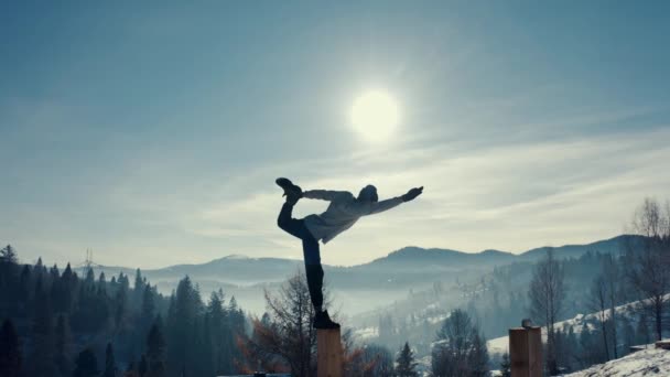 Aerial view, man practicing yoga on the background of winter mountains. — Stock Video