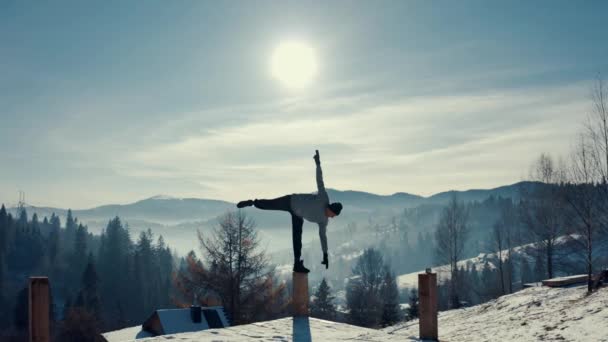 Traveler practicing yoga in the winter mountains and enjoying life. Amazing winter adventure in nature. Aerial view, back light. — Stock Video