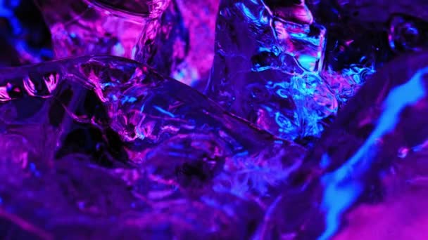 Blok lodu jest oświetlony neonowym niebieskim i różowym w świetle. obraca się tworząc różne pasemka — Wideo stockowe