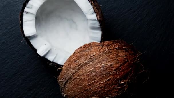 Dividido em duas metades de coco sobre um fundo preto.Coco fresco girando sobre um fundo preto. — Vídeo de Stock