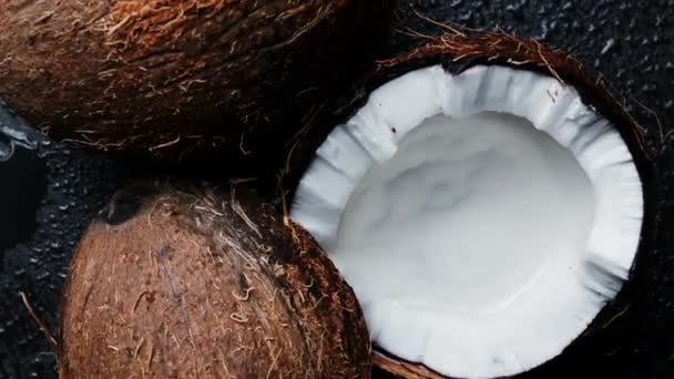 黒の背景に2つの半分のココナッツに分割します。黒の背景に回転する新鮮なココナッツ. — ストック動画