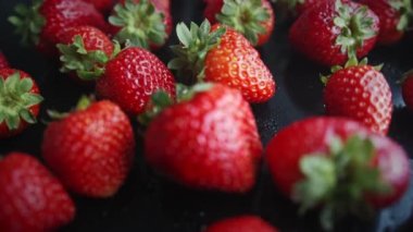 Siyah arka planda çilekler. Doğal ürünler çevre dostudur. Makro çekim