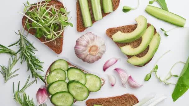 Pikantní avokádové sendviče na celozrnném chlebu. Vegetariánská strava, zdravá strava. byt ležel, horní pohled. — Stock video