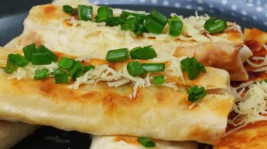 Peynir ve ıspanak parçaları ızgara tortilla ile yeşil soğan ve domatesleri eski ahşap bir tahtaya sarmışlar. Türk yemekleri.