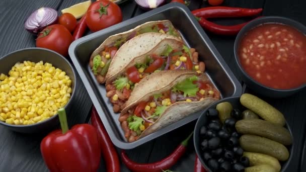 Meksykańskie jedzenie. Tortille tacos z mielonymi warzywami na czarnym tle z innymi daniami i warzywami — Wideo stockowe