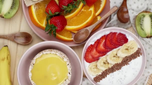 Dulces desayunos. Granola con fresas y plátano y cuñas de naranja recién picadas, decoradas con varias frutas, desayunos dulces — Vídeos de Stock