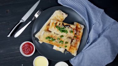 Peynir ve ıspanak parçaları ızgara tortilla ile yeşil soğan ve domatesleri eski ahşap bir tahtaya sarmışlar. Türkçe yemekler. en üstteki görünüm