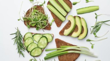 Avokado, humus, salatalık, ayçiçeği filizli sağlıklı sandviçler. Tahta bir kesme tahtasının üzerinde, üst manzara. Sağlıklı Vejetaryen Atıştırması
