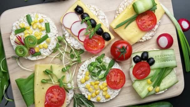 Sandwiches frescos vegetarianos en una tabla de cortar de madera. Rellenos de verduras y hierbas. Vista desde arriba. Vista superior. Rotación. — Vídeo de stock