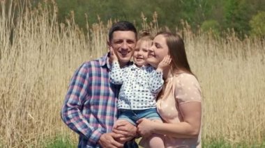 Sazlıkların arka planında kollarında küçük bir kızla mutlu genç bir çift.