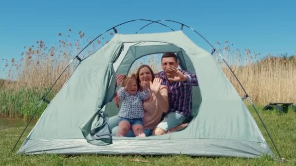 Familia con una niña en la naturaleza descansando en una tienda de campaña turística — Vídeos de Stock