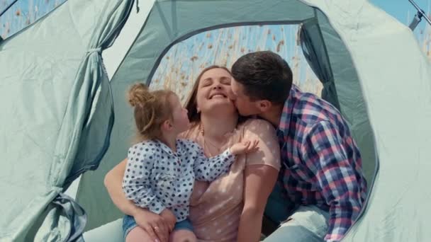 Familia con una niña en la naturaleza descansando en una tienda de campaña turística — Vídeos de Stock