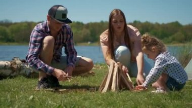 Ailesi bir çadırla nehrin kıyısında dinleniyor. Baba, anne ve kız odun topluyor.