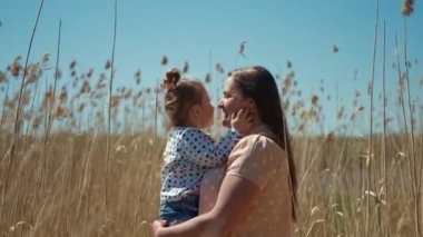 Mutlu, gülümseyen bir kadın sazlıklarda küçük bir kızı tutuyor. Anne kızıyla iyi eğlenceler.