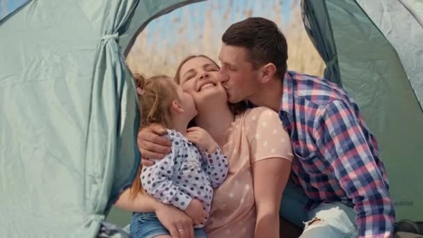 Familia con una niña en la naturaleza descansando en una tienda de campaña turística — Vídeos de Stock