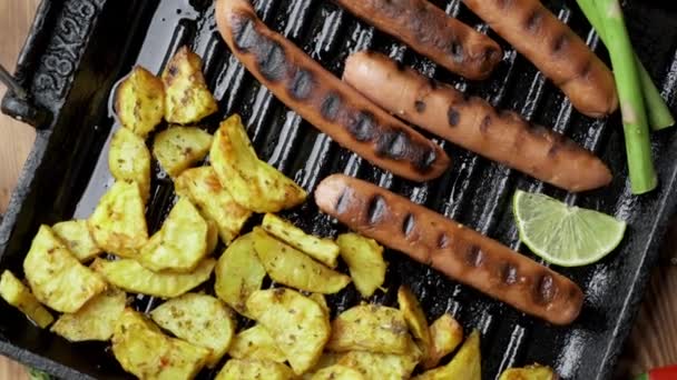 Gebakken aardappelen en gegrilde soja worstjes op donkere houten ondergrond. Plat gelegd. veganistisch fastfood — Stockvideo