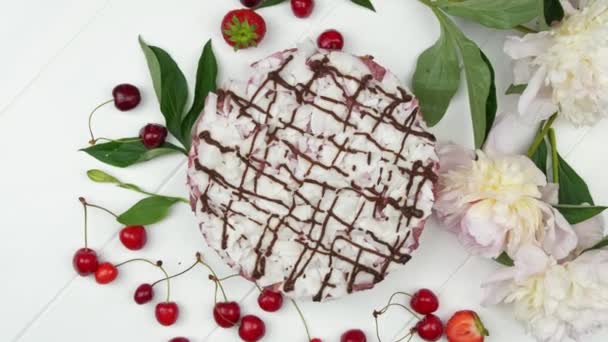 Torta bianca con bacche mature rosse sul tavolo di legno bianco. vista dall'alto — Video Stock