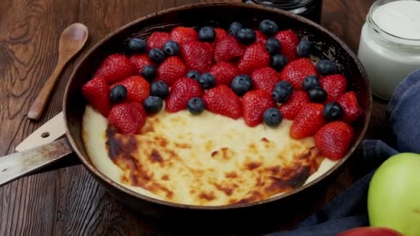 Stekt ostpaj i stekpanna med jordgubbar och blåbär på ett träbord. — Stockvideo