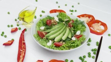 Dilimlenmiş avokadoyla yeşil salata, beyaz ahşap masada taze domatesler, yakın çekim. Sağlıklı diyet vejetaryen yaz vejetaryeni sebze salatası konsepti.