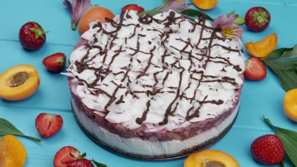 Tarte kelapa di piring putih dengan latar belakang kayu biru. dihiasi dengan irisan aprikot dan strawberry — Stok Video