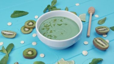 Mavi ahşap arka planda spirulinalı tatlı. Kivi dilimleri, üzerine nane yaprakları serpiştirilmiş limon.