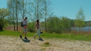 Göl kenarında doğa parkında yürüyen mutlu şirin bir aile. Çocuk yürüten ebeveynler. Göl kenarında aile pikniği. Doğal parkta yürüyüş.