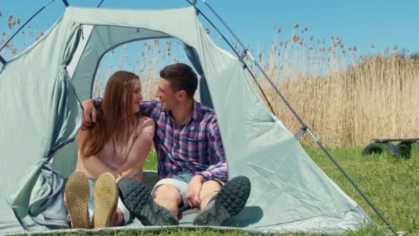 Young couple smile happily at each other while planning a delicious breakfast. Nice morning for a couple at the campsite. — Video