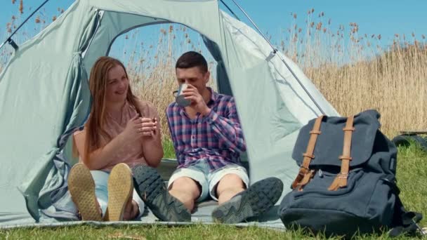 若いカップルが淹れたてのお茶を飲んでいる。キャンプ場での夫婦の快適な朝. — ストック動画