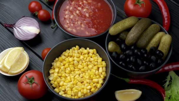 Legumes enlatados em um prato. pepino, milho, feijão. Em uma placa preta — Vídeo de Stock