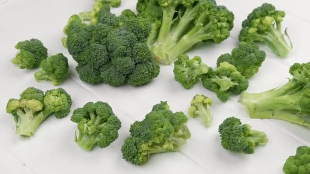 Broccoli utspridda på vitt träbord .Ovanifrån — Stockvideo