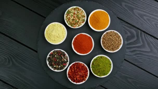 Colorful herbs and spices for cooking. Indian spices. On a black background. Top view — 图库视频影像