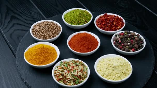 खाना पकाने के लिए रंगीन जड़ी बूटियों और मसाले। भारतीय मसाले। एक काले पृष्ठभूमि पर। शीर्ष दृश्य — स्टॉक वीडियो