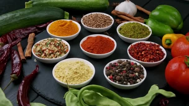 Färgglada örter och kryddor för matlagning. Indiska kryddor. På en svart bakgrund. Ovanifrån — Stockvideo
