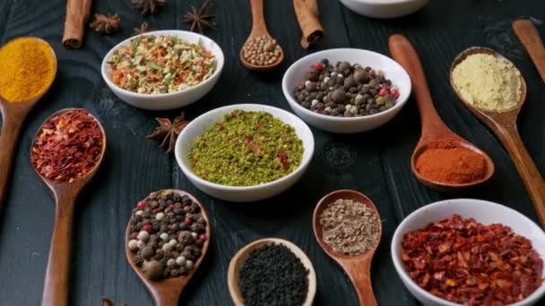 Dry colorful spices in spoons and bowls with fresh seasoning on dark background, top view — 图库视频影像