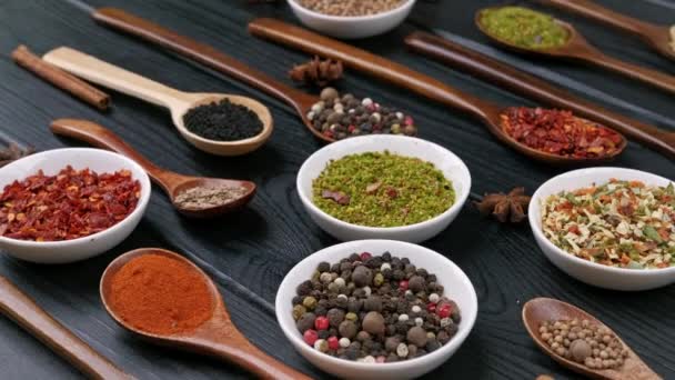 Torra färgglada kryddor i skedar och skålar med färsk krydda på mörk bakgrund, ovanifrån — Stockvideo