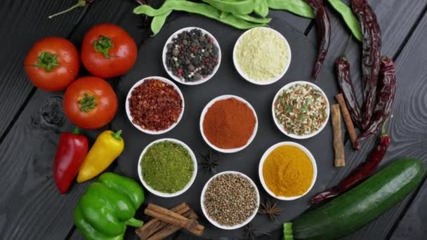 Színes gyógynövények és fűszerek főzéshez. Indiai fűszerek. Fekete háttérrel. Felülnézet — Stock videók