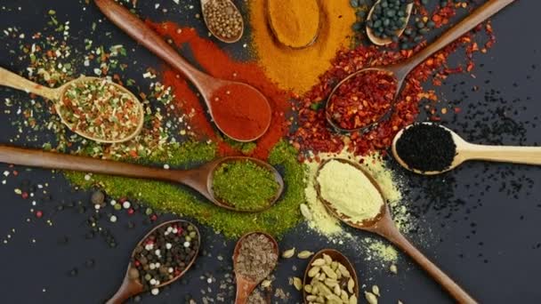 Dry colorful spices in spoons and bowls with fresh seasoning on dark background, top view — 图库视频影像