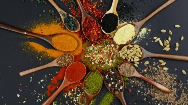 Dry colorful spices in spoons and bowls with fresh seasoning on dark background, top view — 图库视频影像