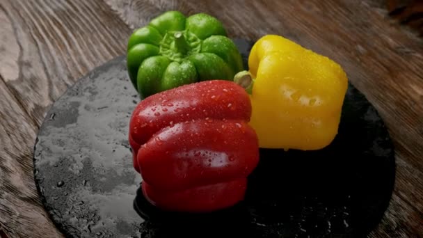 Red yellow orange bell peppers on a wooden cutting board. table top — Stock Video