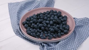 Beyaz arka plandaki seramik tabakta yabanmersini taze böğürtlen.