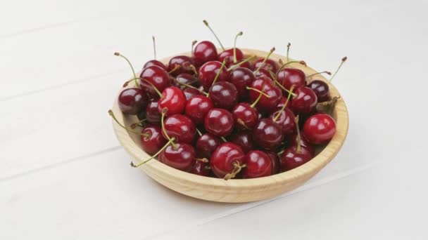 Un tazón de cerezas recién lavadas. Fondo de madera blanca — Vídeos de Stock