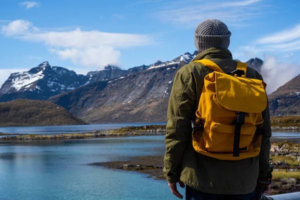 En fyr reiser med gul ryggsekk gjennom pittoreske steder med vakre fjellandskap. stockfoto