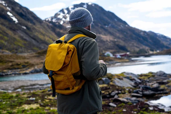 En fyr reiser med gul ryggsekk gjennom pittoreske steder med vakre fjellandskap. stockfoto