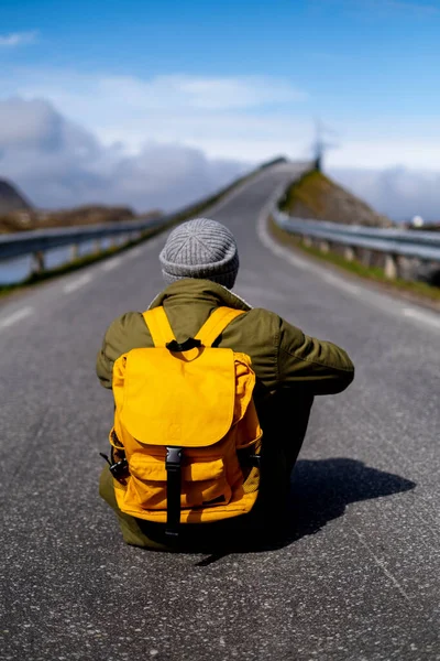 En fyr reiser med gul ryggsekk gjennom pittoreske steder med vakre fjellandskap. royaltyfrie gratis stockfoto