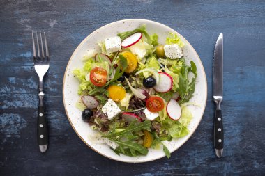 Taze sebzeli, çatal ve bıçakla servis edilen peynirli sağlıklı ve diyet salatası. Üst görünüm