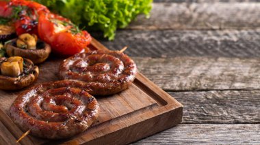 Ahşap bir tahtanın üzerinde sebzeli ızgara sosis. Boşluğu kopyala