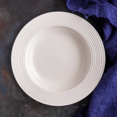 Koyu arkaplandaki boş beyaz plakanın üst görünümü. Boş tabak 