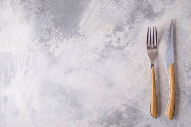 Çatal ve bıçağın üst görüntüsü gri arka planda. Metin için boşluk