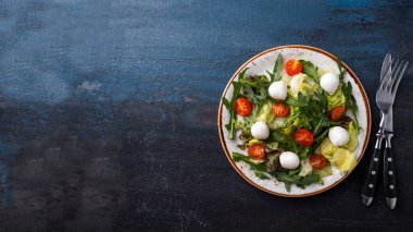 Sebzeli, mozarella peynirli, çatallı ve bıçaklı lezzetli salata. Üst görünüm, metin alanı